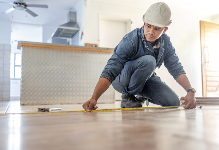 Man measures flooring in home renovation project